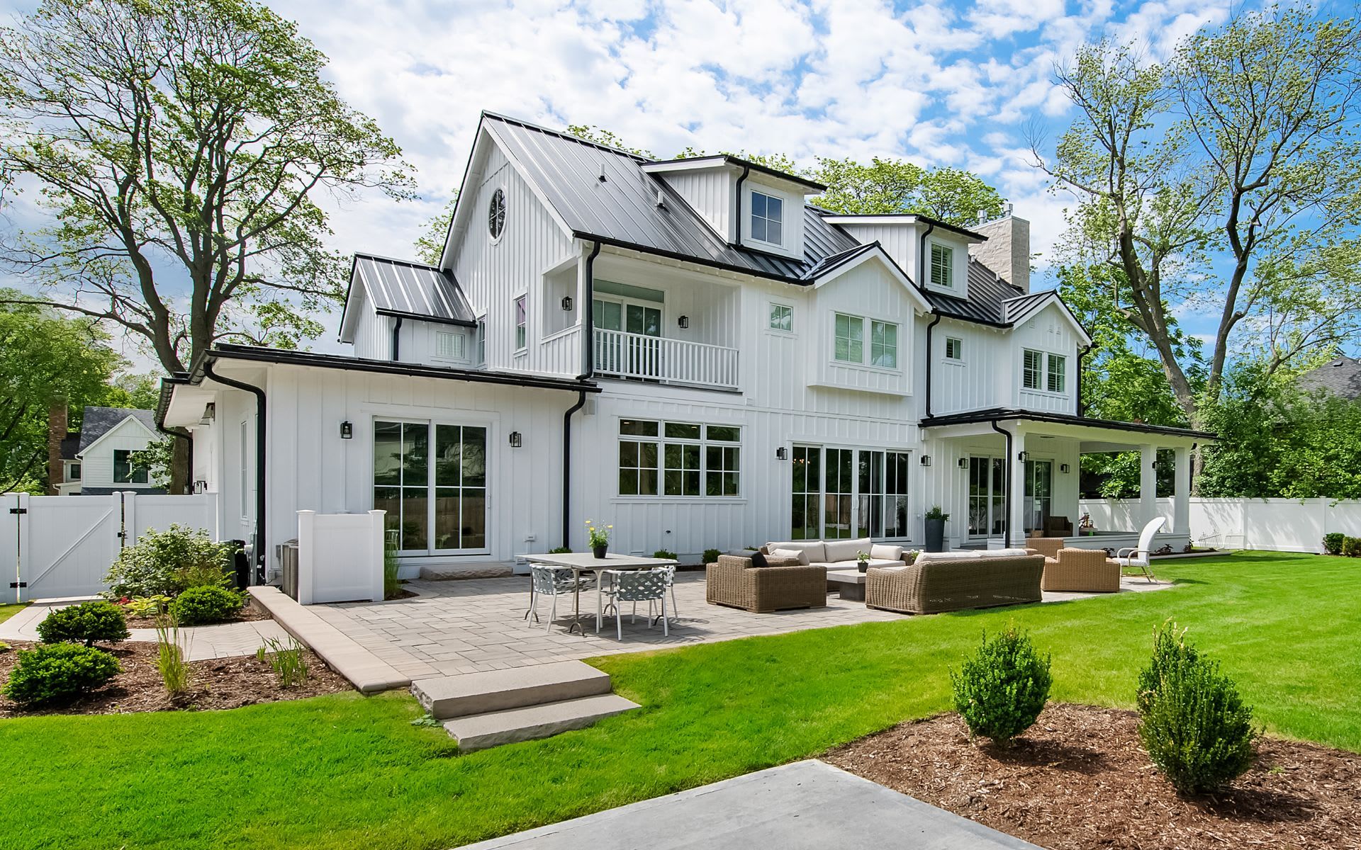 A white farmhouse-style home with a patio and lawn